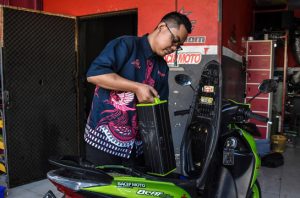 A mechanic in the Indonesian city of Bandung, West Java, replaces the battery of an electric moped (Image: Dimas Rachmatsyah / Alamy)
